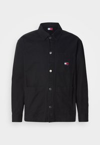 Schwarze Jacke mit Knöpfen aus Köperstoff, mit Kragen, vorderen Taschen und einem kleinen Markenpatch in Rot, Weiß und Blau auf der Brust.