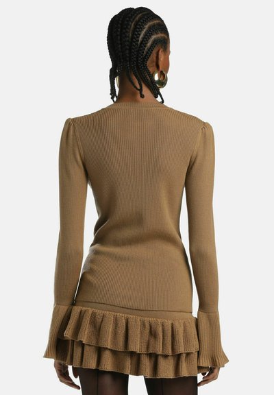 Brūns ribots kleitas svārks ar garām piedurknēm, pieguļošu augšdaļu un izplūdušu volānu apakšdaļu. Mīksta tekstūra, sofistiskots siluets.