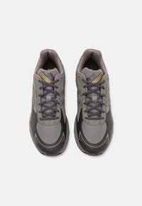 Pár šedých a černých tenisek ASICS Gel-1130 se šněrováním, pohled zvrchu na bílém pozadí.