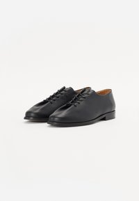 Black leather shoes with a rounded toe, featuring a smooth texture and a lace-up design. The sole is flat and durable.