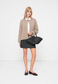 Cardigan en tricot beige, chemise blanche à col, jupe en denim, sac fourre-tout noir et ballerines bordeaux. Design simple et structuré avec des tonalités contrastées.