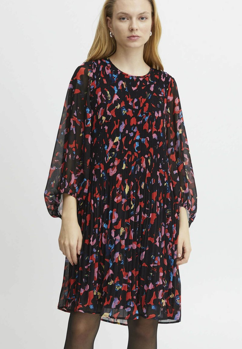 Robe plissée noire avec un motif abstrait multicolore, manches longues bouffantes et col rond. Tissu transparent et coupe mi-jupe.