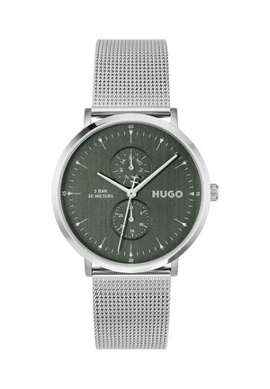 Zilverkleurig horloge met meshband, donkergroene wijzerplaat, zilveren wijzers, twee subwijzerplaten voor dag en seconden, en "HUGO"-logo aan de rechterkant.