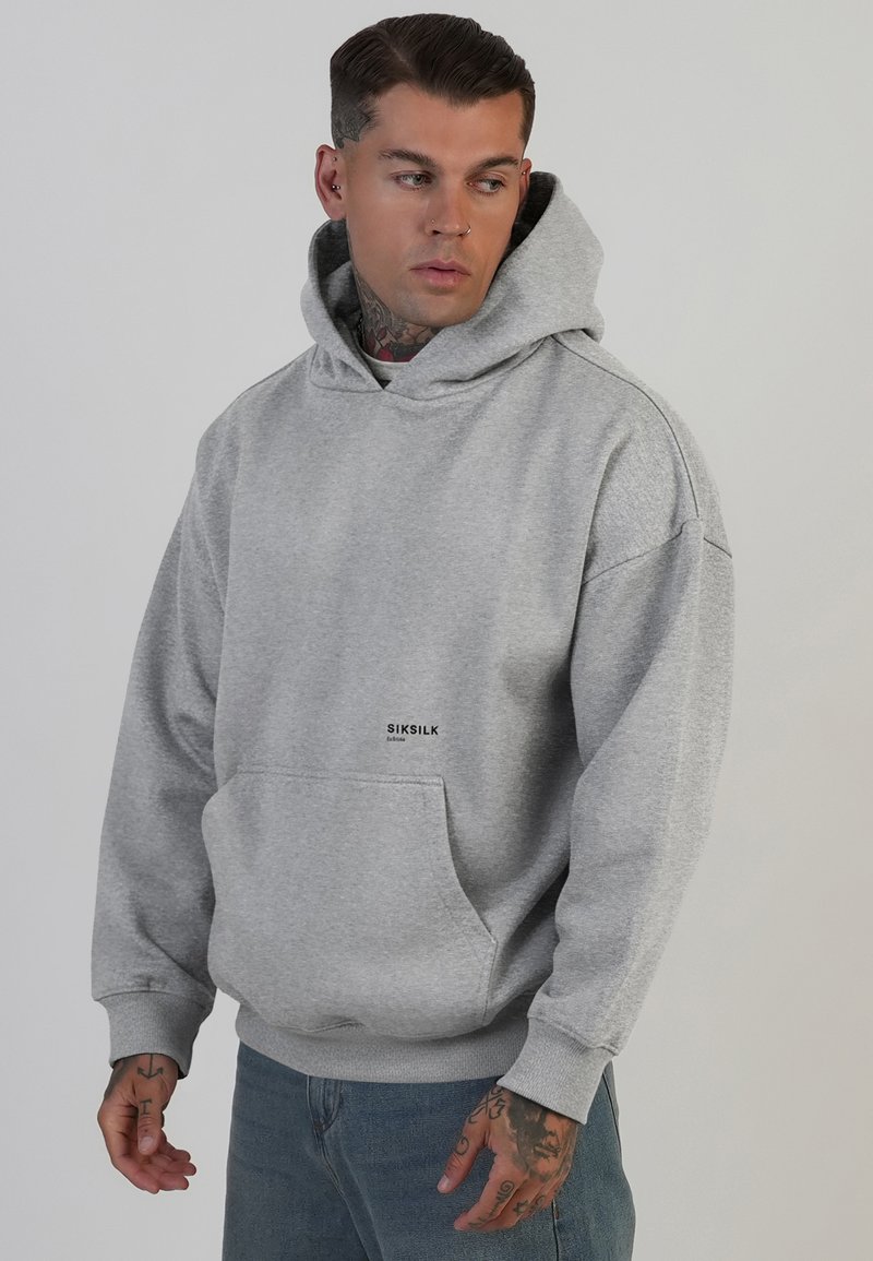 Grauer Hoodie aus weichem Material mit Kängurutasche, gerippten Bündchen und einem Logo auf der Vorderseite. Mit einer Kapuze mit Kordelzug.