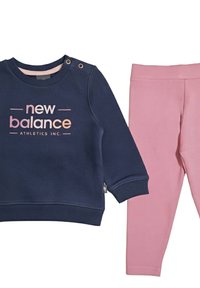 Felpa blu navy con scollatura tonda, accenti di bottoni e logo rosa "New Balance Athletics Inc."; abbinata a leggings rosa.