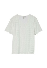 Blouse en coton blanc avec un col en V, des manches courtes à volants et un motif de broderie ajourée. Bords des manches festonnés.
