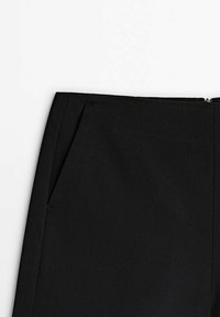 Pantalons noirs en tissu tissé, avec une coupe droite, des poches latérales et une texture lisse, dotés d'une fermeture éclair dissimulée.