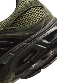 Close-up of olive green and black athletic shoe sole featuring mesh fabric upper and visible air cushioning elements.