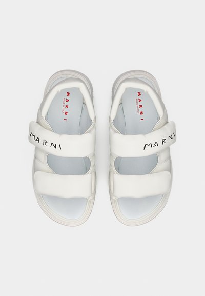 Λευκά δερμάτινα σανδάλια με δύο ρυθμιζόμενους ιμάντες, στρογγυλερή μύτη, επενδεδυμένο εσωτερικό πέλμα και λαστιχένια σόλα. Το λογότυπο «Marni» είναι τυπωμένο σε μαύρο χρώμα στον ιμάντα.
