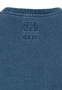 Tessuto di denim blu scuro con una superficie testurizzata. Presenta un collo cucito e dettagli del marchio in rilievo sul retro.