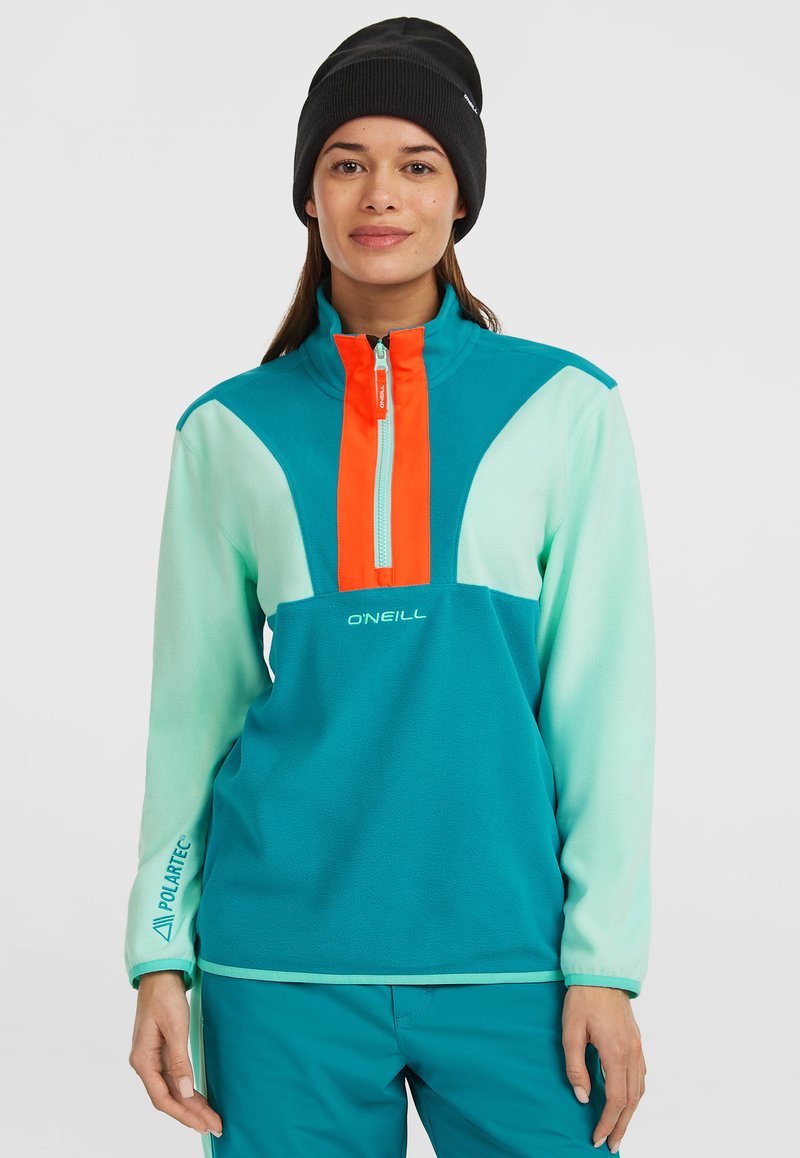 Teal-Fleece-Pullover mit einem halben Reißverschlusskragen, orangefarbenen Akzenten und weißem Logo. Verfügt über kontrastierende Ärmel und ein "Polartec"-Detail an den Bündchen.