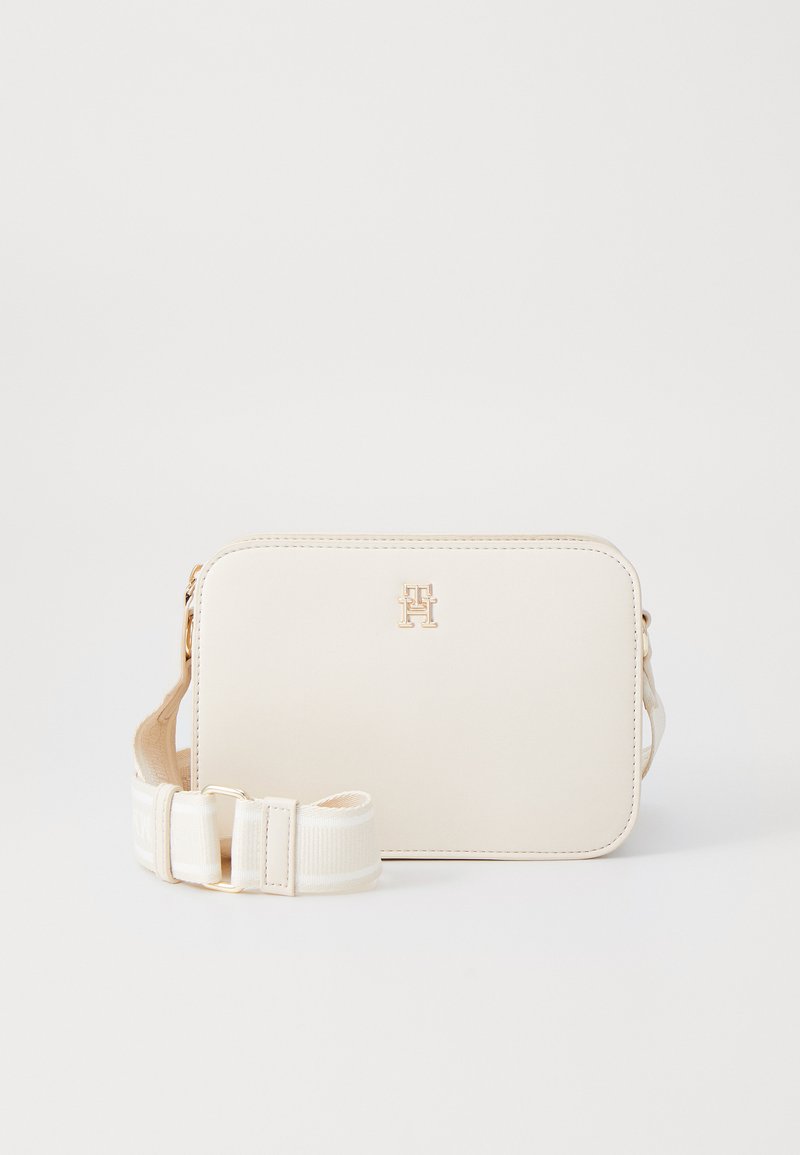 Hvit syntetisk crossover-bag med et gulllogo, rektangulær form, og en justerbar stropp med logo-trykk. Glatt tekstur, minimale detaljer.