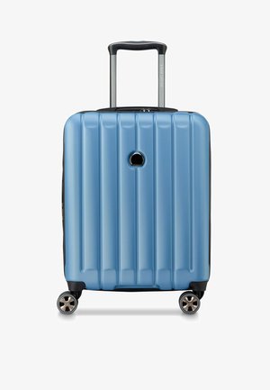 Maleta de mano de concha dura en azul claro con diseño acanalado vertical, acentos en negro, un mango telescópico y cuatro ruedas giratorias.
