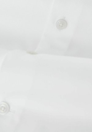 Tissu blanc avec deux boutons transparents visibles cousus dessus, montrant une partie d'un vêtement ou d'un article textile plié.