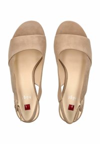 Sandalias de cuña de ante beige con diseño de punta abierta, cintas anchas, cortes en los laterales y un pequeño acento rojo en el tacón.
