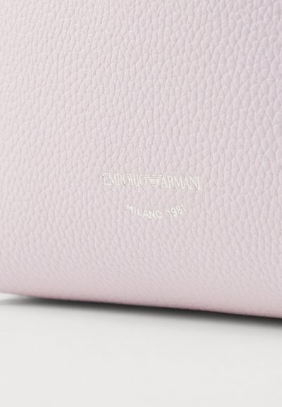 Cuero texturizado de color rosa claro con la marca en relieve "EMPORIO ARMANI MILANO 1981" en blanco, mostrando un acabado suave y blando.