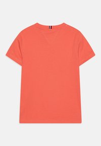 Korale bawełnowa koszulka z krótkim rękawem, okrągłym dekoltem i małym szwem w kształcie V z tyłu. Gładka tekstura, minimalna liczba szwów i brak grafik.