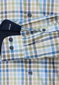 Geruite shirt met blauwe, groene en beige vierkanten; heeft blauwe knopen en een contrasterende donkere kraag; katoenstof met een gladde textuur.