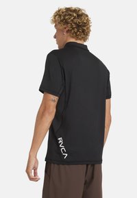 Czarna koszulka polo z krótkim rękawem i kołnierzykiem, z białym logo RVCA z lewej strony. Wykonana z gładkiego, oddychającego materiału.