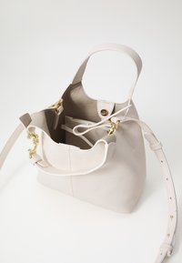 Emmerstijl handtas gemaakt van gestructureerd wit leer, met gouden hardware, een schouderband en een ruime binnenkant met een ritszak.
