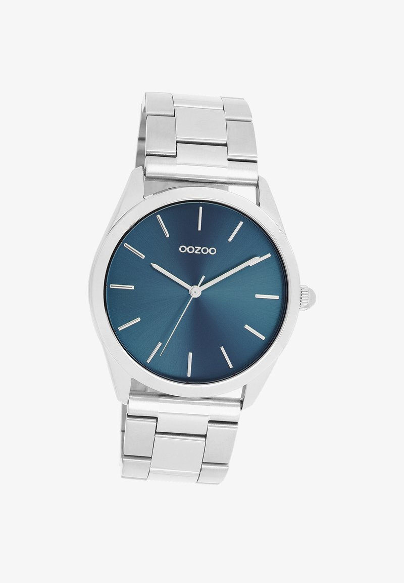 Montre en acier inoxydable argenté avec un cadran rond dégradé bleu, des index horaires argentés minimalistes et un bracelet en maillons métalliques poli.