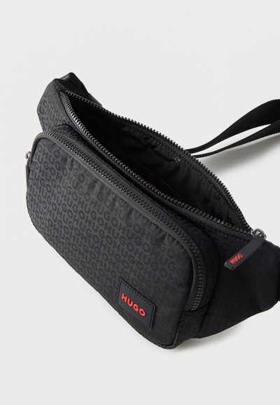 Banane noire de marque Hugo avec motif monogramme, poche avant zippée, compartiment principal ouvert et sangle réglable.