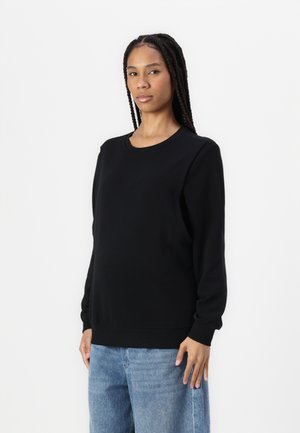 Black sweatshirt with a round neckline, long sleeves, and ribbed cuffs. Fabric appears smooth and soft. Paired with light blue jeans.