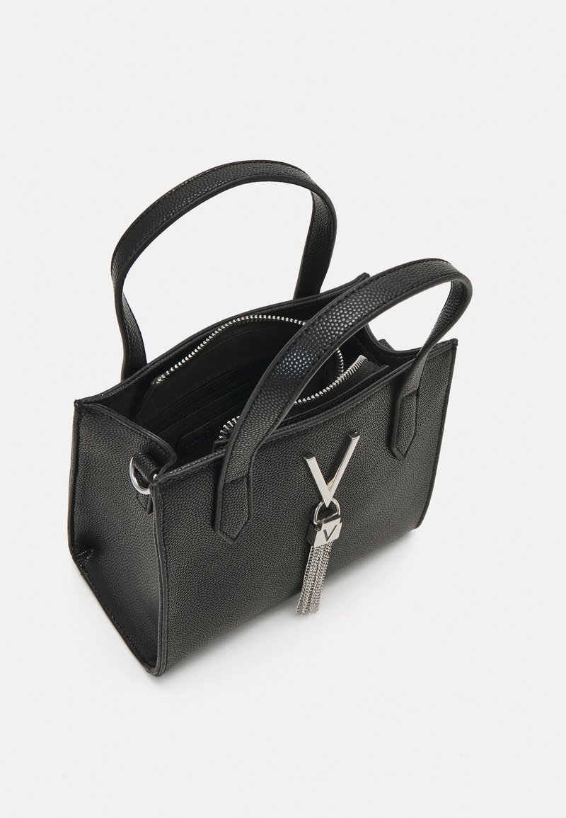Schwarze strukturierte Handtasche mit zwei kurzen Griffen, silbernen Beschlägen, Reißverschluss und dekorativem Troddel mit einem "V"-Anhänger.