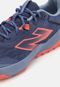Chaussure de course marine et corail avec tige en maille, logo contrasté, semelle extérieure en caoutchouc et accents texturés sur le côté et la boîte à orteils.
