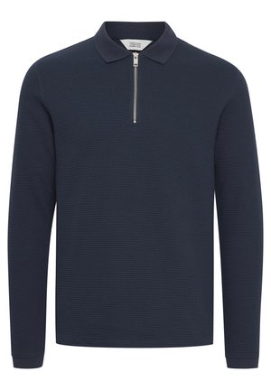 Marineblå langærmet polo-shirt i tekstureret stof, med halv-zip foran og flad krave. Har ribbede manchetter og en lige kant.