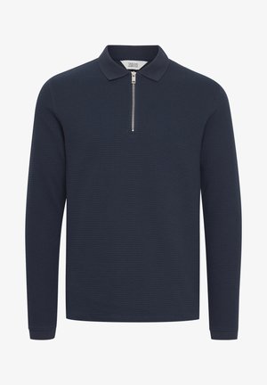 Mornarska polo majica z dolgimi rokavi, izdelana iz teksturirane tkanine, s pol zapiranjem na zadrgo spredaj in ravnim ovratnikom. Ima rebraste manšete in ravno rob.