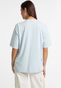 Lyseblå kortærmet T-shirt lavet af blød bomuld, med rund halsudskæring og en afslappet pasform, set fra ryggen.