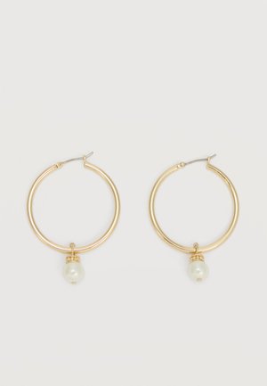 Χρυσά σκουλαρίκια στεφάνης, καθένα με μια μοναδική λευκή πέρλα που κρέμεται και μικρή λεπτομέρεια από στρογγυλό στρας σε ανοιχτό φόντο.