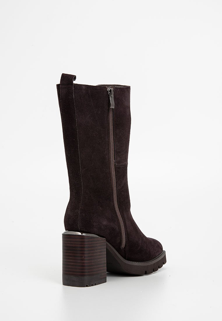 Brązowy zamszowy botek za kostkę z klinowym obcasem, bocznym zamkiem błyskawicznym i teksturowaną podeszwą. Charakteryzuje się wysokim, smukłym krojem i zaokrąglonym noskiem.