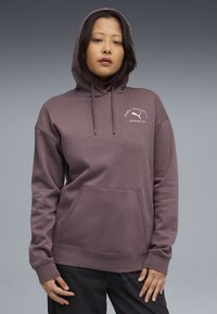 Sweatshirt cu glugă în violet estompat, realizat dintr-un material moale. Dispune de o buzunar frontal și logo-ul "Puma Athletic" în alb pe piept.