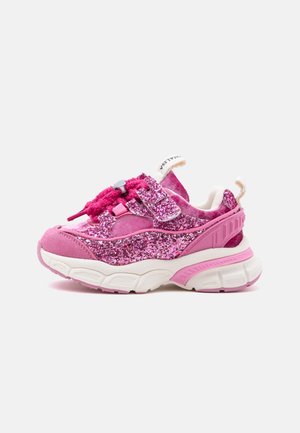Basket enfant rose avec détails pailletés, semelle blanche épaisse, bride réglable et languettes de tirage sur la languette et le talon.