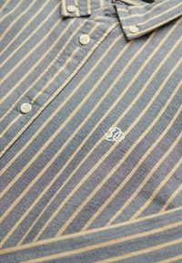 Stribet polo-shirt i blå og gul. Har knapper og et lille broderet logo. Lavet af struktureret stof med et klassisk kravedesign.