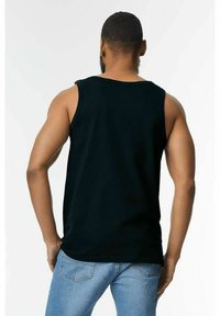 Svart ärmlös linne med en avslappnad passform, tillverkat av mjukt tyg, med rund halsringning och jämn yta. Bärs tillsammans med blå jeans.