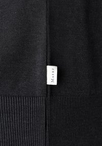 Maglione nero con texture a costine e corpo liscio. Presenta un'etichetta intrecciata con la scritta "Maerz" sulla cucitura laterale. Design semplice e minimalista.