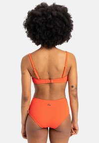 Oranžový rebrovaný bikini set s bandeau vrchom a nastaviteľnými ramienkami a vysokými nohavičkami. Obsahuje detail značkového loga.