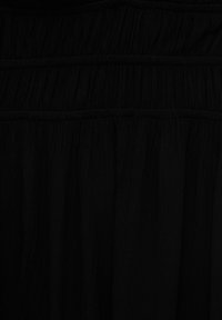 Schwarzer, strukturierter Stoff mit gerafften Partien und elastischen Abschnitten. Das Material wirkt leicht und fließend, mit dezenten Falten.