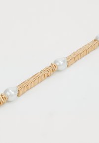 Guldtonet armbånd med skiftende rektangulære metalled og to uregelmæssige hvide perler, med en glat, poleret overflade.