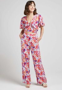 Ensemble deux pièces à imprimé floral comprenant un top court noué à neckline en V et un pantalon large, principalement dans des nuances de rose, violet et orange.