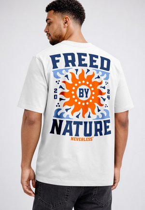 Mann trägt weißes T-Shirt mit orangefarbener Sonne und blauem Schriftzug „Freed by Nature“ und „Neverless“ auf der Rückseite.