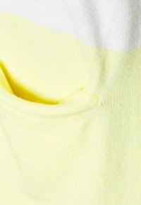 Strickkleidungsstück mit horizontalen Streifen in Weiß und leuchtendem Gelb. Taschendetail aus gelbem Stoff, weiche Textur und mittlere Dicke.