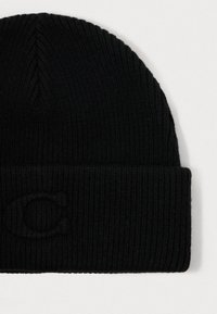 Juodas megztas beanie su raukšlėta tekstūra ir sulenkta apykakle, priekyje su iškilniu "C" logotipu. Minkštas vilnos ir sintetinių pluoštų mišinys.
