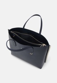 Laivastonsininen nahkainen olkalaukku, jossa on kaksi kahvaa, vetoketjusuljenta ja sisäisiä lokeroita. Laukussa on kuvioitu vuori ja kullanväriset metalliosat.