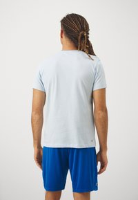 Sky blue short-sleeve t-shirt made of soft fabric, with a crew neck and plain design, paired with blue athletic shorts.