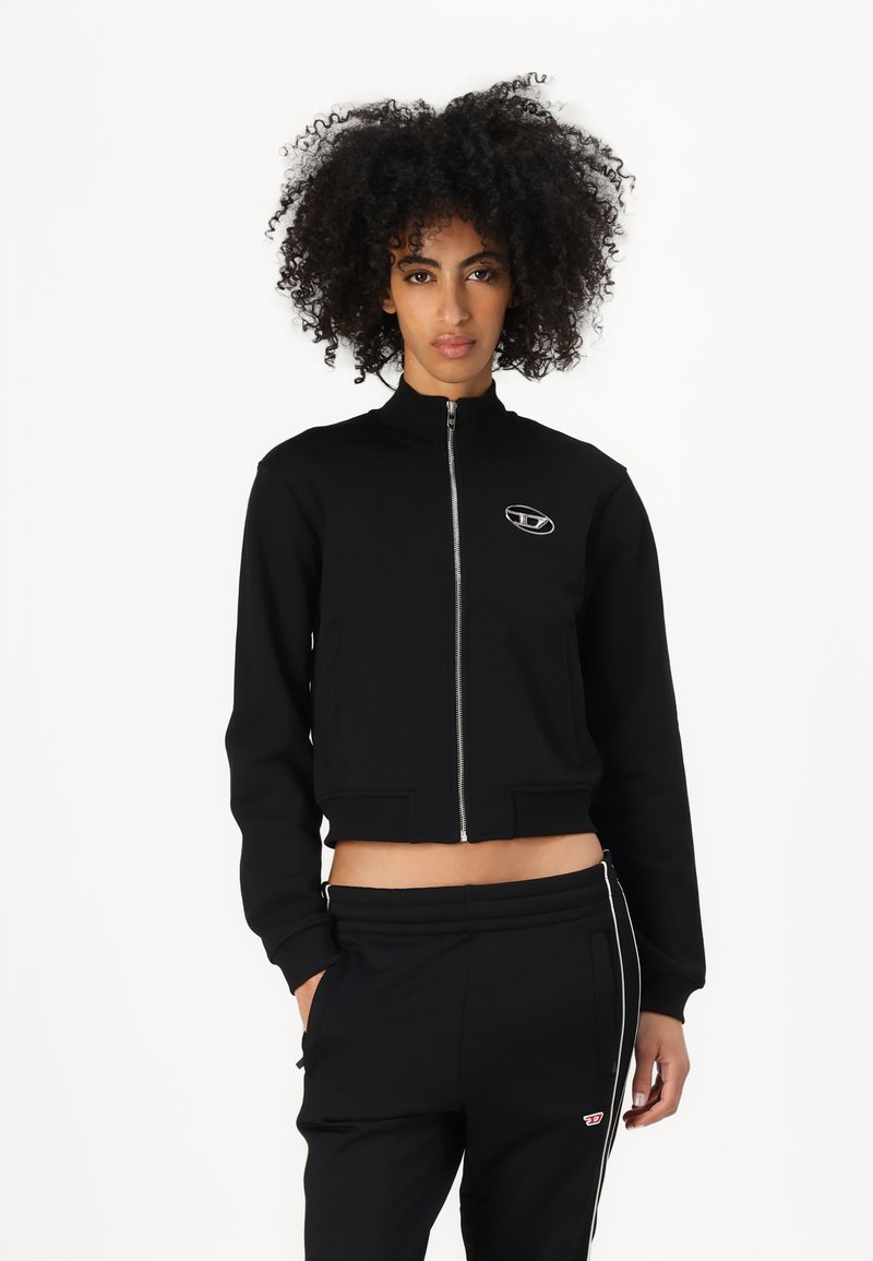Black cropped jacket with a high collar, front zipper, and logo detail. Soft fabric with ribbed cuffs and waistband.