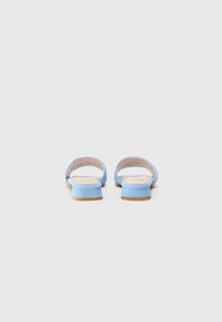 Scarpe slip-on in suede blu con tacco basso, parte posteriore aperta e rivestimento interno morbido. Presentano un design elegante e minimalista.